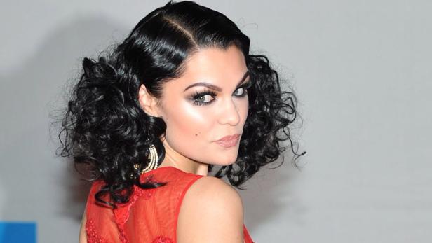 Die Sängerin Jessie J mit lockigem, dunklem Haar und rotem Kleid blickt über ihre Schulter.