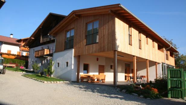 Ein modernes Holzhaus mit überdachter Terrasse und Sitzgelegenheiten.