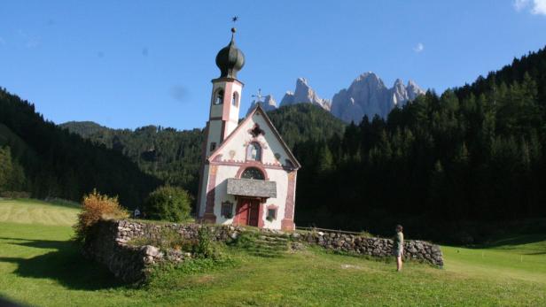 Die Kirche St. Johann in Ranui vor der Geislergruppe in den Dolomiten.