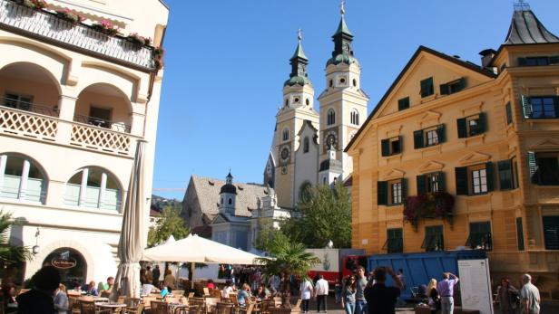 Der Dom von Brixen überragt einen belebten Platz mit Cafés und Restaurants.