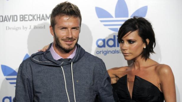 David und Victoria Beckham posieren vor einem Adidas-Logo.