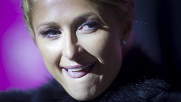 Nahaufnahme von Paris Hilton, die in die Kamera lächelt und ihre Zunge herausstreckt.