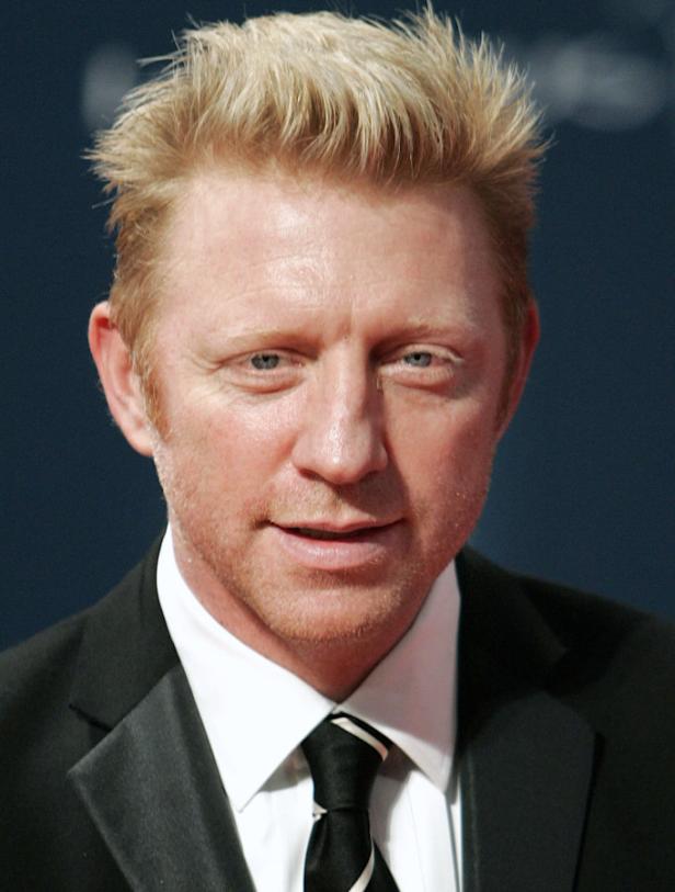 Ein Porträt von Boris Becker in einem schwarzen Anzug mit Krawatte.