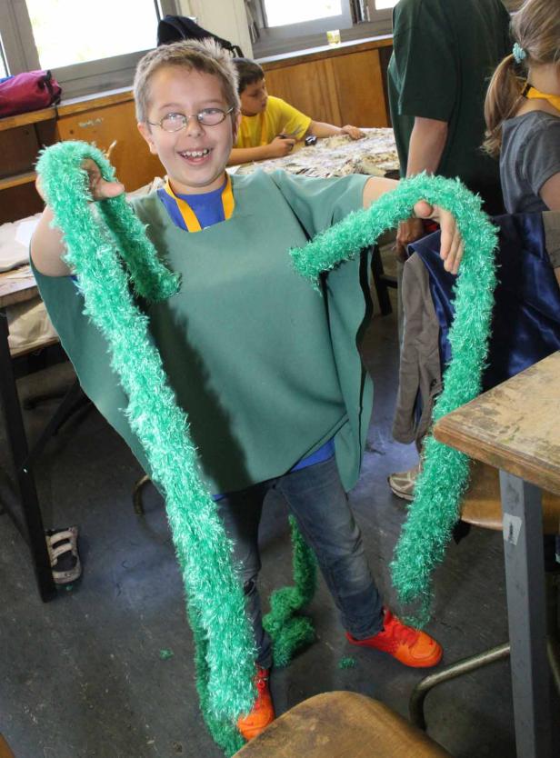 Ein lächelnder Junge mit Brille posiert mit einer grünen, zotteligen Boa.