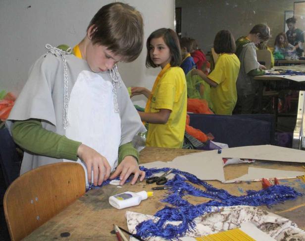 Eine Gruppe Kinder bastelt an Kostümen in einem Raum.