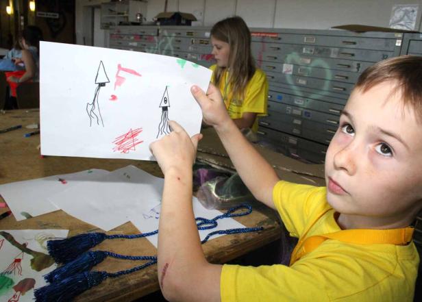 Ein Junge zeigt eine Zeichnung von zwei Tintenfischen.