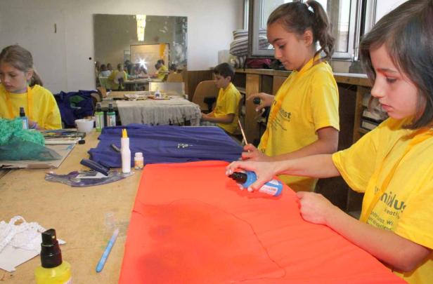 Kinder bemalen in einem Workshop Stoffe mit Farbe.