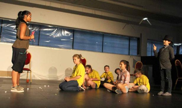 Eine Gruppe von Kindern führt ein Theaterstück auf einer Bühne auf.