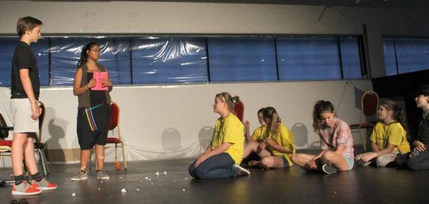 Eine Gruppe Jugendlicher probt ein Theaterstück auf einer Bühne.