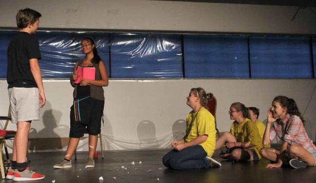 Eine Gruppe von Jugendlichen probt ein Theaterstück auf einer Bühne.