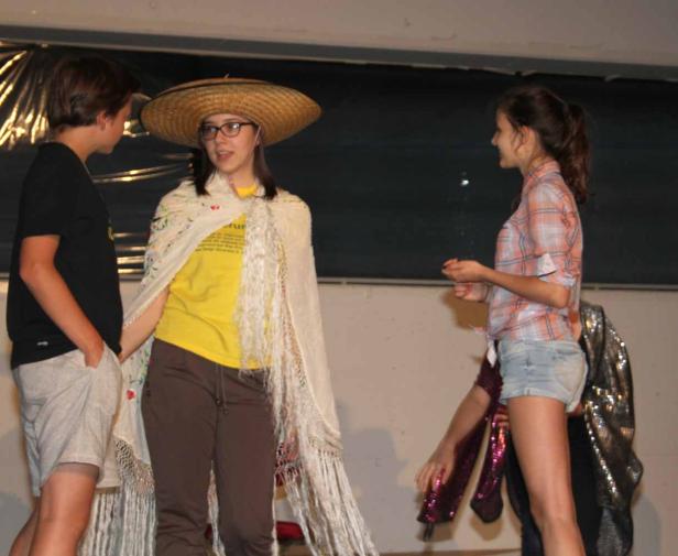 Drei Jugendliche stehen auf einer Bühne, eines davon mit Sombrero und Tuch behangen.