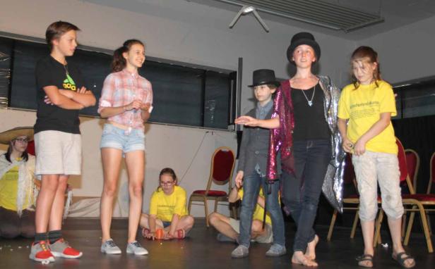 Eine Gruppe von Kindern steht auf einer Bühne, einige in Kostümen.