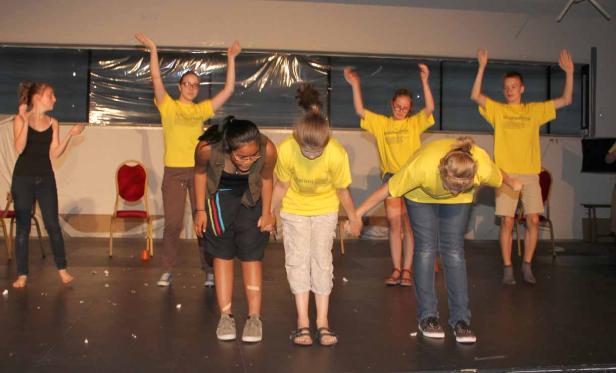 Eine Gruppe junger Leute verbeugt sich auf einer Bühne.