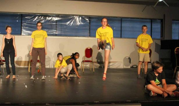 Eine Gruppe von Jugendlichen steht und sitzt auf einer Bühne.