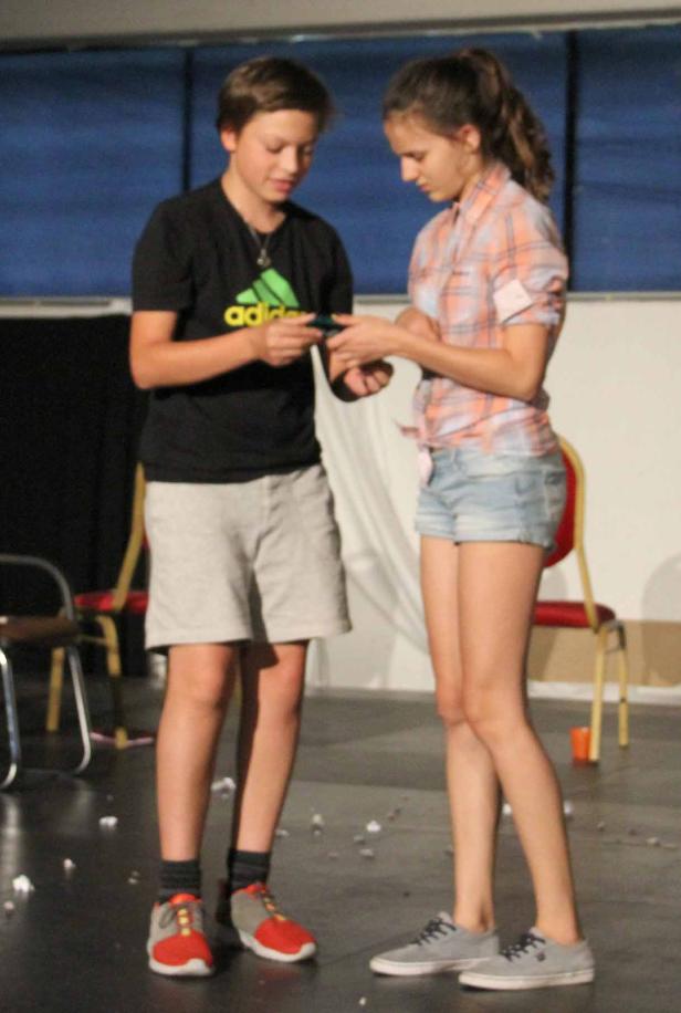 Ein Junge und ein Mädchen stehen zusammen und schauen auf ein Handy.