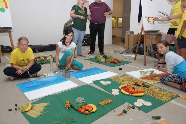Kinder malen Bilder mit Obst und Gemüse als Vorlage.