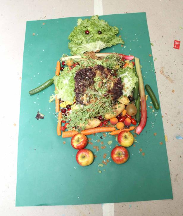 Ein Roboter, der aus verschiedenen Obst- und Gemüsesorten auf einem grünen Hintergrund besteht.