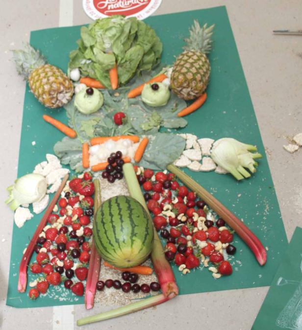 Ein Gesicht aus Obst und Gemüse, darunter Ananas, Erdbeeren und Karotten.