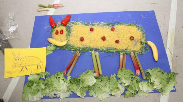 Eine Kuh aus Gemüse und Obst liegt auf einem blauen Untergrund.