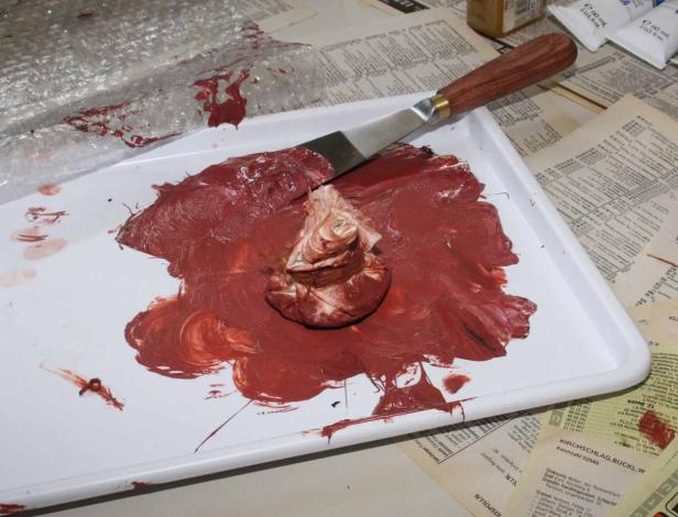 Eine Palette mit roter und weißer Ölfarbe und einem Malmesser.