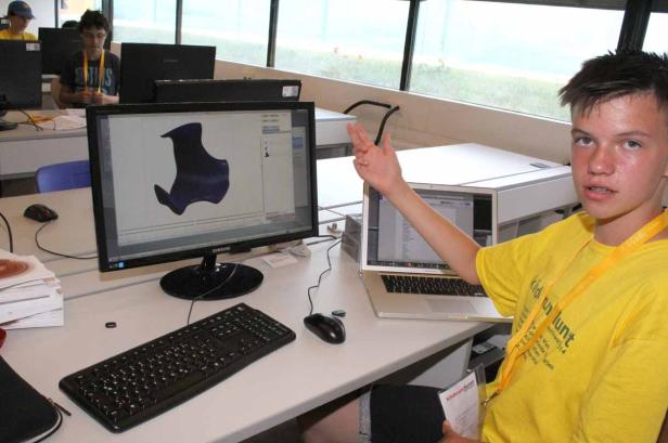 Ein Jugendlicher erklärt ein 3D-Modell auf einem Computerbildschirm.