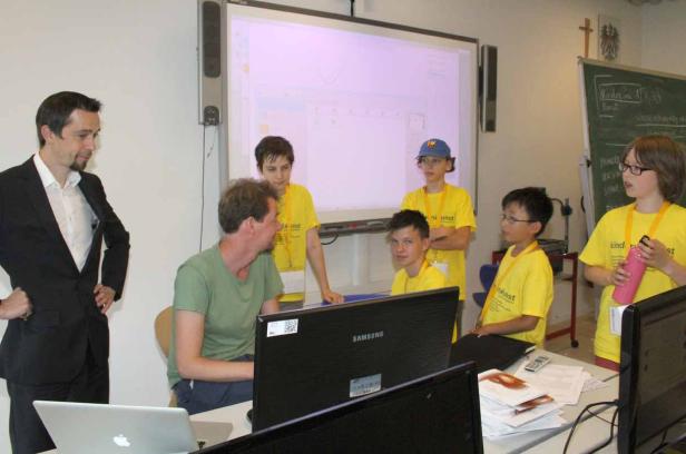 Eine Gruppe von Schülern arbeitet mit einem Lehrer an Computern im Klassenzimmer.