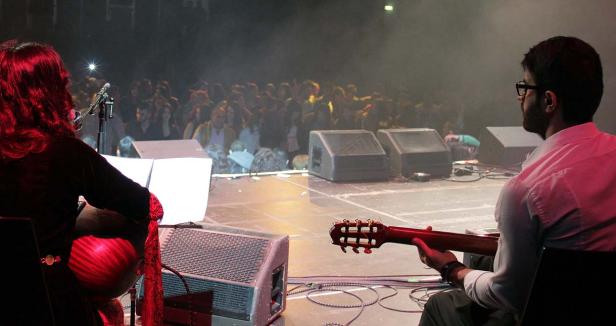 Zwei Musiker sitzen auf der Bühne vor einem Publikum.