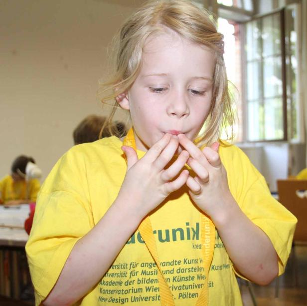 Ein blondes Mädchen versucht, mit den Fingern zu pfeifen.
