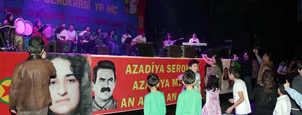 Eine kurdische Musikgruppe tritt auf einer Bühne vor einem Publikum auf.