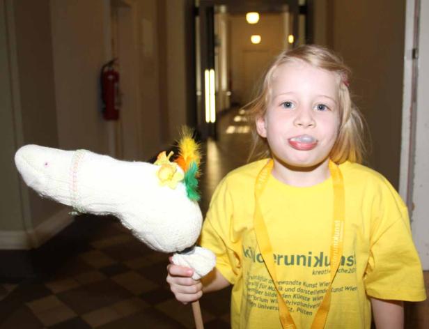 Ein blondes Mädchen mit einem Steckenpferd im Flur.
