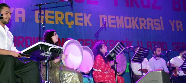 Eine kurdische Musikgruppe tritt vor einem Banner mit der Aufschrift „Ya Gerçek Demokrasi Ya“ auf.