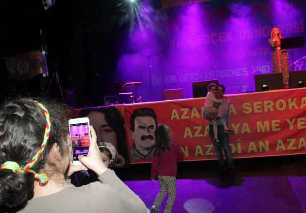 Eine Frau filmt mit ihrem Smartphone eine Sängerin auf der Bühne.