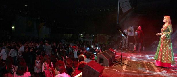 Eine Sängerin tritt vor einem großen Publikum auf einer Bühne auf.