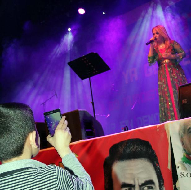 Eine Sängerin tritt auf einer Bühne mit lila Licht auf, während ein Kind ein Foto macht.