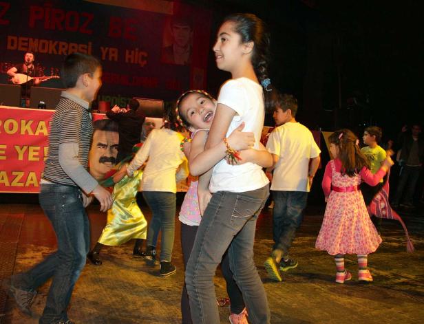 Eine Gruppe Kinder tanzt auf einer Bühne vor einem Banner.