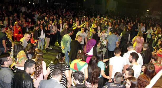 Eine große Menschenmenge tanzt und feiert auf einer Bühne.