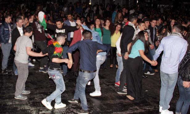 Eine Gruppe von Menschen tanzt Hand in Hand in einer Menschenmenge.