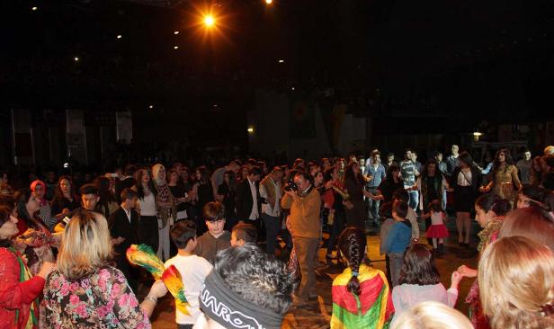 Eine große Gruppe von Menschen tanzt und feiert in einer Halle.