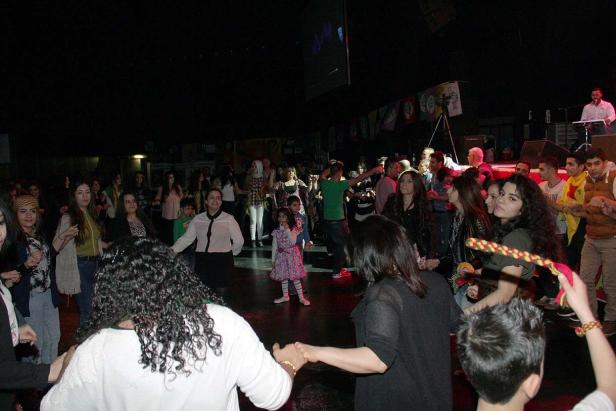 Eine Gruppe von Menschen tanzt im Kreis in einem dunklen Raum.