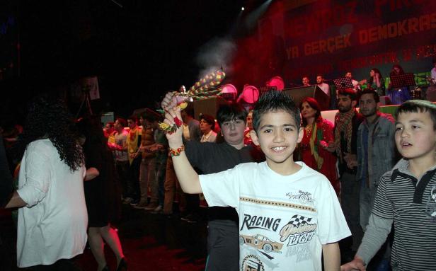 Ein lächelnder Junge hält eine traditionelle Nowruz-Fackel in die Höhe.