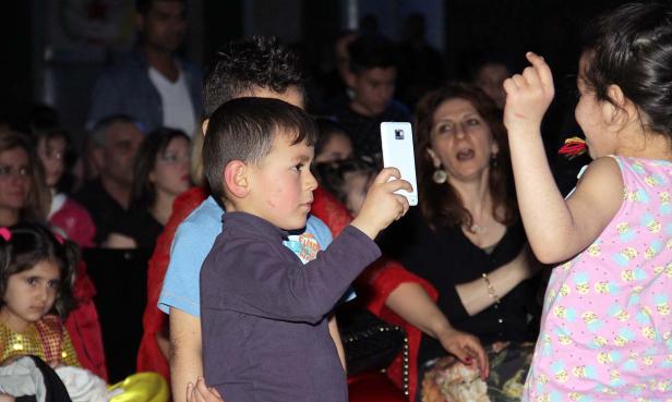 Ein Junge macht mit seinem Smartphone ein Foto von einem Mädchen.