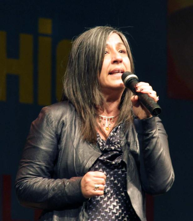 Eine Frau mit grauem Haar spricht in ein Mikrofon.