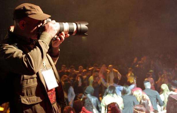 Ein Fotograf mit Mütze fotografiert eine Menschenmenge.