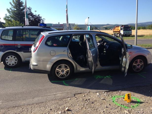 Ein silberner Ford Focus steht mit geöffneten Türen neben einem Polizeiauto.