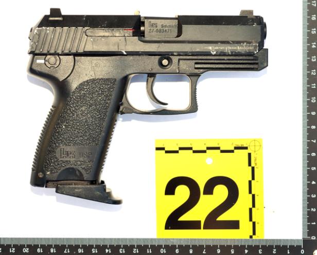 Eine schwarze H&K USP Pistole liegt neben einem gelben Beweismittelmarker mit der Nummer 22.