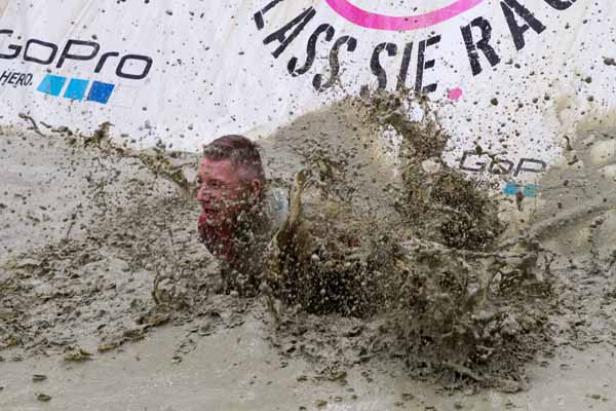 Ein Mann kriecht während eines Rennens durch den Schlamm.