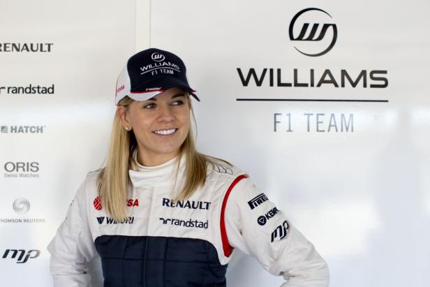 Eine Frau im Williams F1 Team-Outfit lächelt in die Kamera.