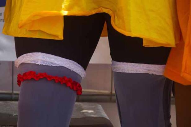 Nahaufnahme von Beinen mit Strumpfbändern unter einem gelben Rock.