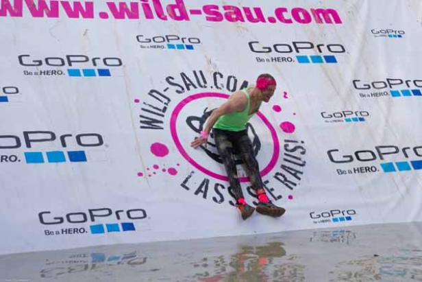 Ein Mann klettert bei einem „Wild Sau“-Hindernislauf eine Rampe hoch.