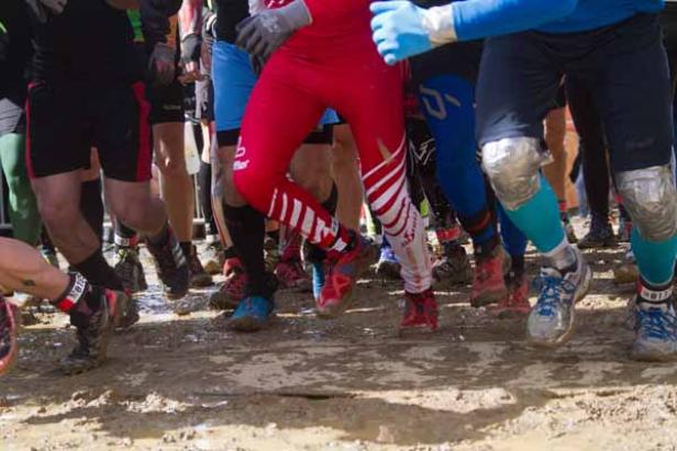 Mehrere Läufer laufen durch schlammiges Gelände.